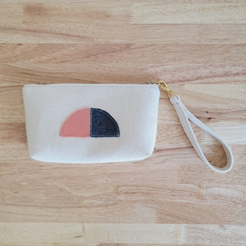 Simple clutch in a natural unbleached cotton. Texture in fabric has its natural nubby look. The Clutch has detachable wristlet strap made from same fabric as the clutch. It is also decorated with a fabric half sun, moon. 