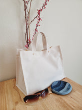 Load image into Gallery viewer, A cleaner cotton Tote bag designed with golden accents to show case the beautiful nature fabric.  This fabric is from CA Cloth Foundry in a natural color with cotton web handles. Medium size travel tote.
