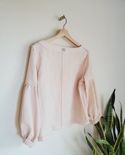 Load image into Gallery viewer, Pink linen blouse shown hanging inside out showing all seems sewn in french seam finish.
