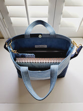 Load image into Gallery viewer, Denim tote bag carries a journal, tablet, coin purse and sunglasses case. Can be carried with crossbody strap. Handmade with repurposed denim in lovely shades of blue. 
