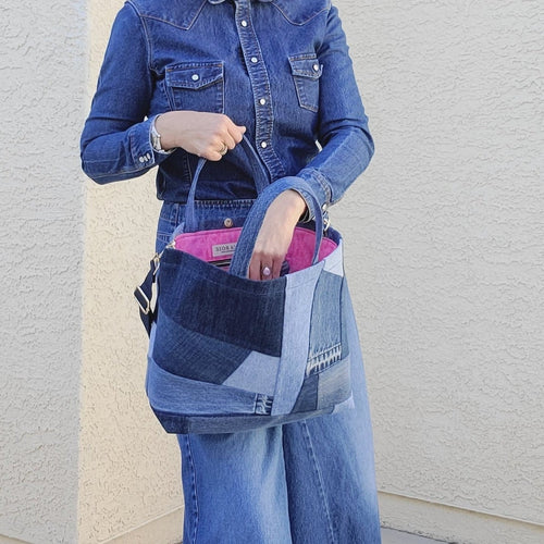 Gray haired women wearing Denim on Denim Outfit and boots.  Women holding a Patchwork denim tote bag with shoulder strap attached to bag.