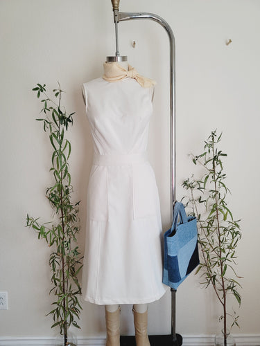 Effortless dress is cut to a soft A-line shape for a sense of ease. The dress is on a dressform, styled with a soft yellow necktie bandana, tan boots and denim tote.  Large side patch pockets, Organic cotton twill in a natural cream color, not dyed. Large side patch pockets. calf length.