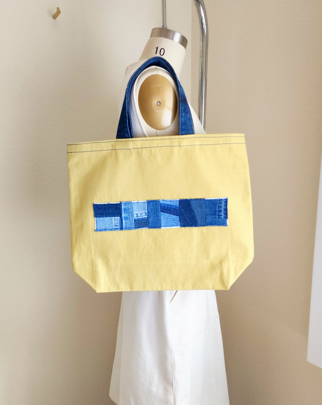 Large yellow denim tote bag with patchwork blue denim band on the front for decor. Blue denim waist band as handles.