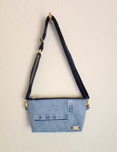 Load image into Gallery viewer, Crossbody bag showing hanging from the dark blue shoulder stap that also connects to wristlet band.  Repurposed denim to a natural luxury look. The look is soft contemporary look in repurposed denim. Great as a vegan choice.
