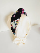 Load image into Gallery viewer, Festive Day of the dead headband in black.  The headband is sitting on a head mannequin.  The print on headband are glittery sugar skulls, roses, and swallow bird.
